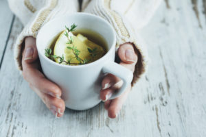 hands holding a hot cup of lemon water